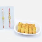 Soft Ajwain Biscuits with Designer White Beaded Rakhi and Auspicious Ganesha Rakhi